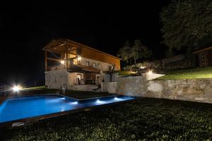 une maison avec une piscine la nuit dans l'établissement Abraços dos Avós - Casas do Monte, à Vila Verde