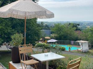 a table and chairs with an umbrella and a pool at HALTE à Reyrieux in Reyrieux