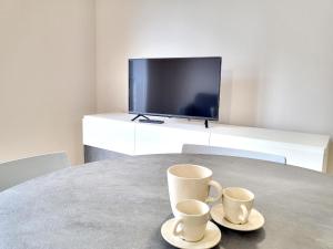 dwie filiżanki kawy siedzące na stole z telewizorem w obiekcie Rho Mind Fiera House w mieście Rho