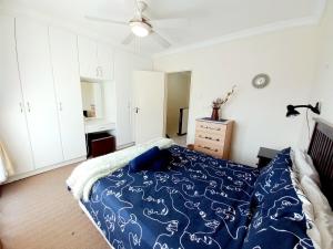 a bedroom with a bed with a blue comforter at 57 Settler Sands Beach Apartment in Port Alfred