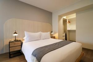 1 dormitorio con cama blanca y cabecero de madera en La Mar Miraflores by Wynwood House, en Lima