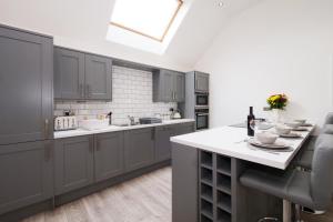 Hoxne Cottages - Sunflower Cottage with private hot tub في يورك: مطبخ بدولاب رمادي وقمة بيضاء