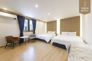 a hotel room with two beds and a table and chairs at Hotel Torang Jeonju in Jeonju