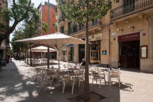 a tables and chairs with an umbrella on a street at Port VII Apt centrico acogedor w balcon 23 in Barcelona