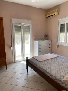 a bedroom with a bed and a dresser and windows at Strati's beach house in Lakkíon