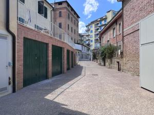 an alley with two green garage doors and buildings at Locanda Castellini-private parking in Siena