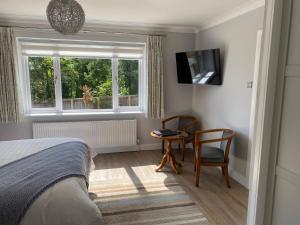 a bedroom with a bed and a chair and a window at Conifers in Lyme Regis