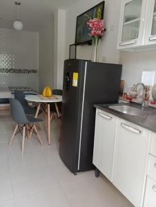 a kitchen with a black refrigerator and a table at Apartahotel Eden Coveñas in Coveñas
