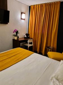 um quarto de hotel com uma cama e uma cortina amarela em The Originals City, Hotel Ariane, Toulouse em Toulouse