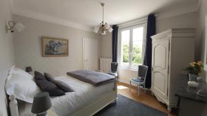 um quarto com uma cama com almofadas e uma janela em La Villa des Tilleuls em Cambremer