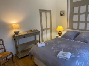 a bedroom with a blue bed and a table and lamp at Le Domaine de Toussacq in Villenauxe-la-Petite