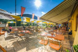 eine Außenterrasse mit Tischen, Stühlen und Sonnenschirmen in der Unterkunft DEVA Hotel Alpenglück in Weißbach
