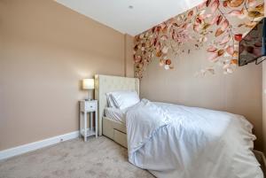 1 dormitorio con 1 cama con una pintura floral en la pared en Viewtopia House en Whittington