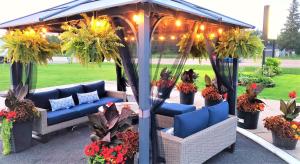 a gazebo with blue couches and plants and lights at Knights Inn Colonial Fireside Inn in Pembroke