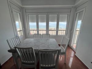 een eetkamer met een tafel, stoelen en ramen bij El Popet de Baix a Mar in Torredembarra