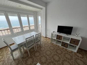 a dining room with a white table and a television at El Popet de Baix a Mar in Torredembarra
