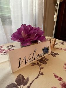 um sinal de boas-vindas sentado numa mesa com uma flor em Apartment Surya em Rogoznica