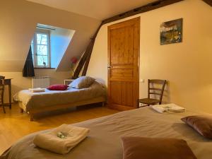 a bedroom with two beds and a wooden door at Le Domaine de Toussacq in Villenauxe-la-Petite