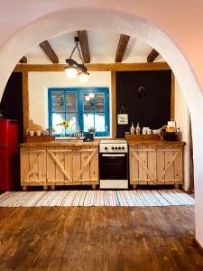 a kitchen with an archway with a stove and a sink at Inside, The Village- Bibliotheca in Tunari