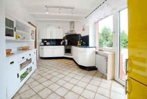 a kitchen with white cabinets and a large window at Ferienwohnung Rhönblick in Hilders
