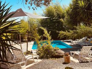 a swimming pool with two lawn chairs and an umbrella at Casa Rico Frade Garden in São Pedro do Corval