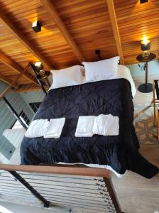 a bedroom with a large bed with black sheets and white pillows at Chalé Rosa Vermelha in Urubici