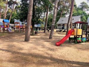 a playground with trees and a red slide at Holiday house near the sea in Pobierowo for 4 people in Pobierowo