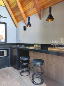 a kitchen with two black stools at a counter at Chalé Rosa Vermelha in Urubici