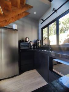 a kitchen with a stainless steel refrigerator and a window at Chalé Rosa Vermelha in Urubici