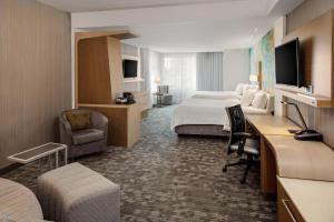 um quarto de hotel com um quarto com uma cama e uma secretária em Courtyard by Marriott Detroit Farmington em Farmington Hills