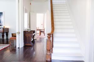 una escalera en una casa con paredes blancas y suelo de madera en Woodbourne Inn en Niagara on the Lake