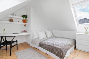 a white bedroom with a bed and a desk at Nydelig toppleilighet med terrasse midt i sentrum in Bergen