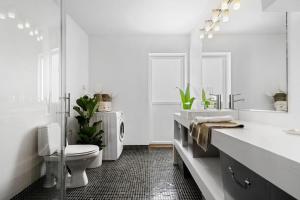 a white bathroom with a toilet and a sink at Nydelig toppleilighet med terrasse midt i sentrum in Bergen