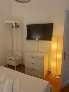 een slaapkamer met een bed en een dressoir met een televisie aan de muur bij DormiTrieste City Life Apartment in Trieste