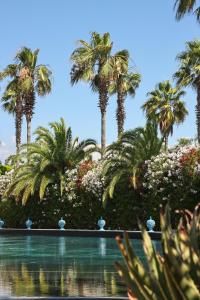 - une piscine bordée de palmiers et de fleurs dans l'établissement Savoy Hotel & Spa - Preferred Hotels & Resorts, à Paestum