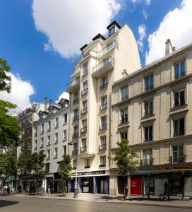 - un grand bâtiment blanc dans une rue de la ville dans l'établissement Libertel Canal Saint Martin, à Paris