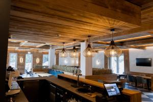 a large room with wooden ceilings and pendant lights at Hotel INA in Borşa