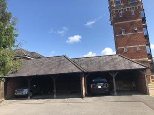 a garage with two cars parked in front of a tower at Amazing converted water tower! in Coulsdon