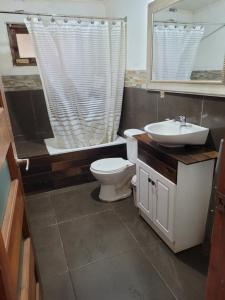 een badkamer met een toilet, een wastafel en een spiegel bij Casa Cueva Cardonal in Curanipe
