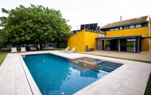 a swimming pool in a yard with a yellow building at Masia Cal Sisplau, con piscina y rodeada de viñedos a 10 minutos de Vilafranca del Penedés, Barcelona ,Cataluña in San Martín Sarroca