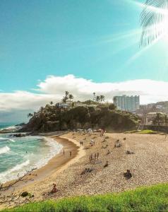 um grupo de pessoas em uma praia perto do oceano em Quarto Suíte Orla Salvador BA em Salvador