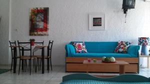 a living room with a blue couch and a table at Aegialis Studios & Rooms in Galissas