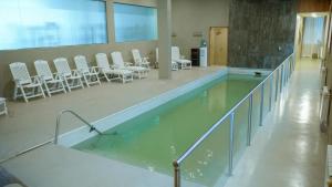 uma piscina de água com cadeiras brancas num edifício em Hotel Canal Beagle em Ushuaia