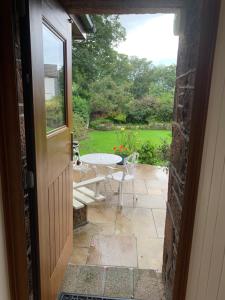 eine offene Tür zu einer Terrasse mit einem Tisch und Stühlen in der Unterkunft Brookfield Cottage in West Kirby