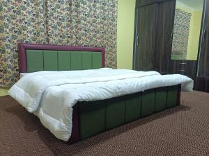 1 cama grande en un dormitorio con cabecero verde en Coachman HomeStay, en Srinagar