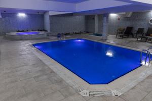 a large swimming pool in a hotel room with a blue pool at Afyon MCG Marble Hotel in Afyon