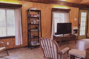 ein Wohnzimmer mit einem TV und einem Schreibtisch mit einem Computer in der Unterkunft Family Fishing Stay - Private Cahaba River Access 