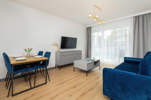 a living room with a table and a blue couch at Apartment Starowiejska with Balcony & Parking next to Gdańsk Arena Stadium by Renters in Gdańsk