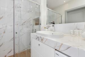 a white bathroom with a sink and a shower at Apartment Starowiejska with Balcony & Parking next to Gdańsk Arena Stadium by Renters in Gdańsk