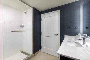 a bathroom with a sink and a shower and a mirror at Residence Inn Long Island Garden City in Garden City